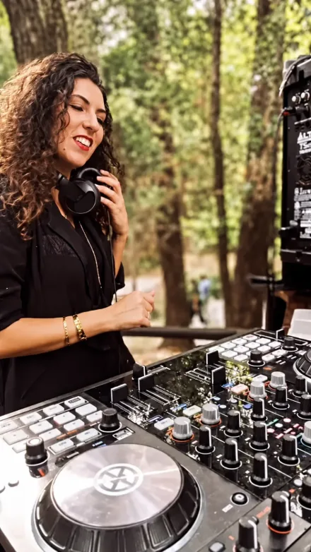 DJ Angie Soul a atuar ao ar livre, sorridente, com os auscultadores ao ouvido junto à mesa de mistura