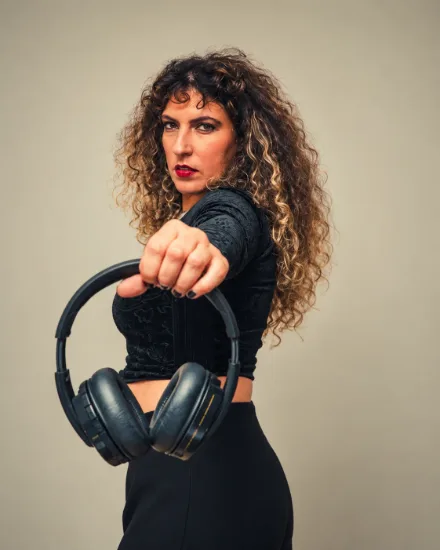 Retrato da DJ Angie Soul a estender os auscultadores em direção à câmara